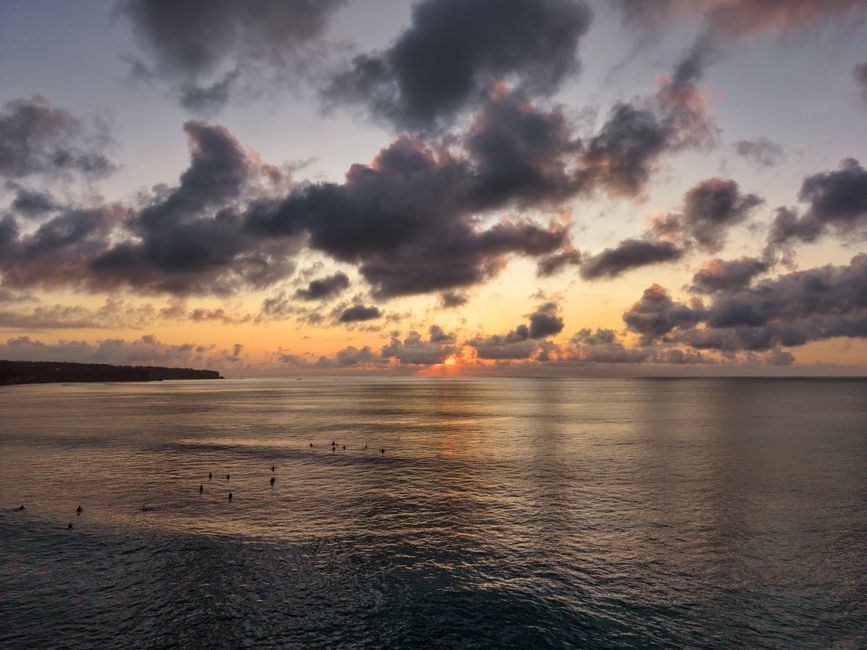 Serene Bali sunset with paddlers on the ocean, capturing tranquil beauty.