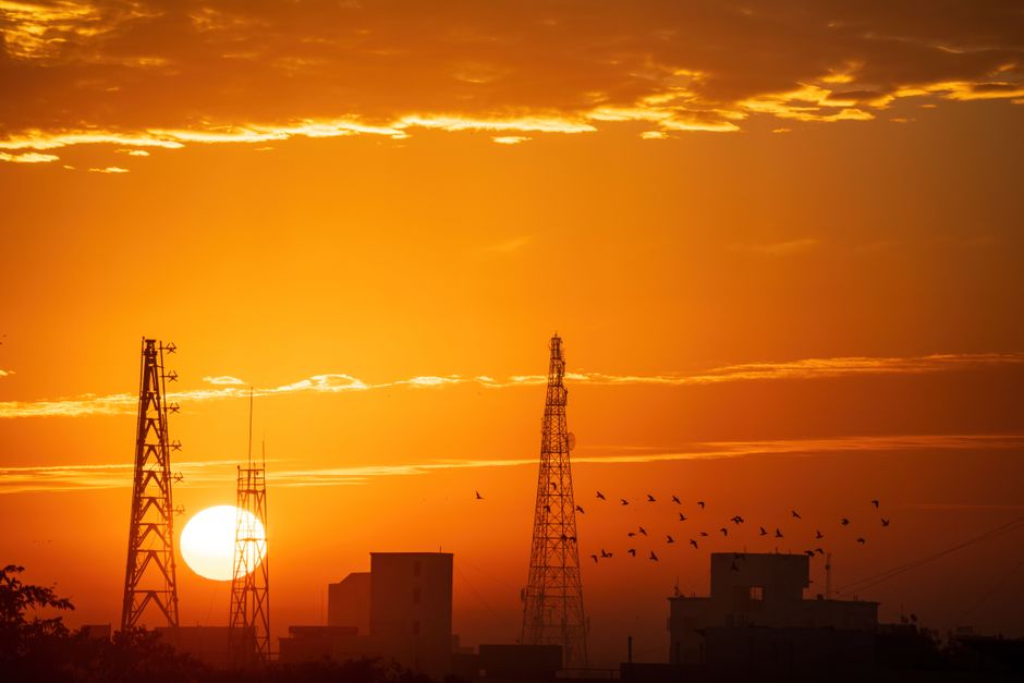 Dramatic sunset with silhouettes of towers and birds, creating a picturesque skyline.