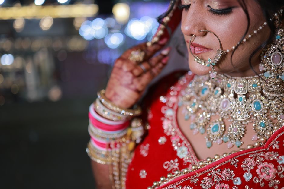 Close-up of an Indian bride adorned with intricate jewelry and Mehndi, wearing a red lehenga.