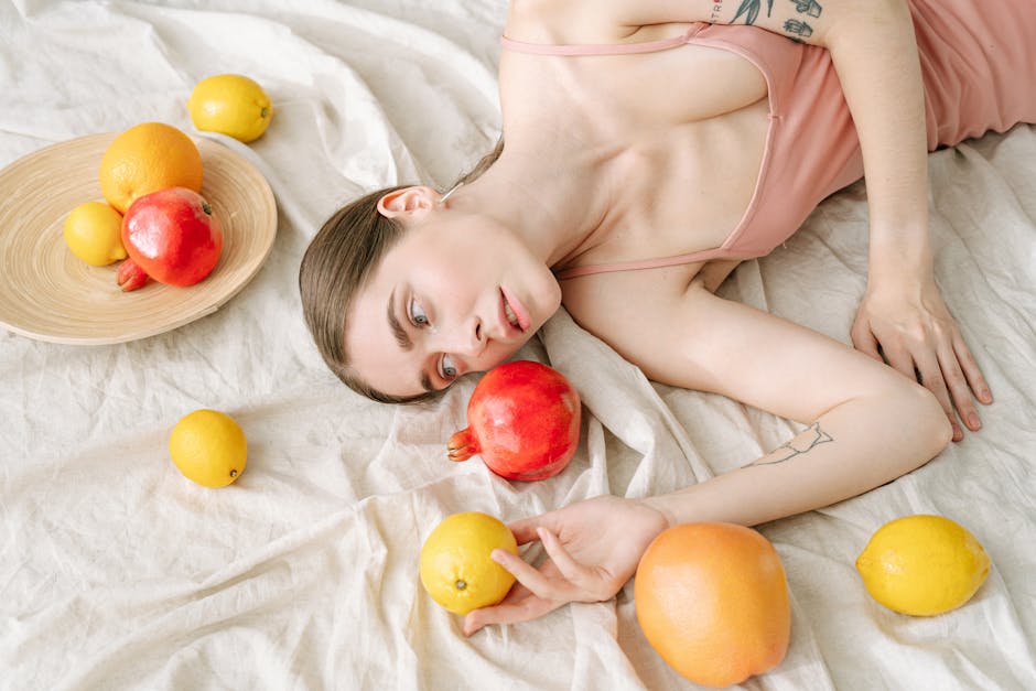 A serene woman in pink lies among vibrant citrus fruits on a soft linen cloth.