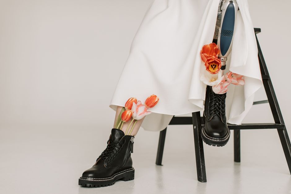 Stylish prosthetic leg paired with floral details and black boots against a minimalist backdrop.
