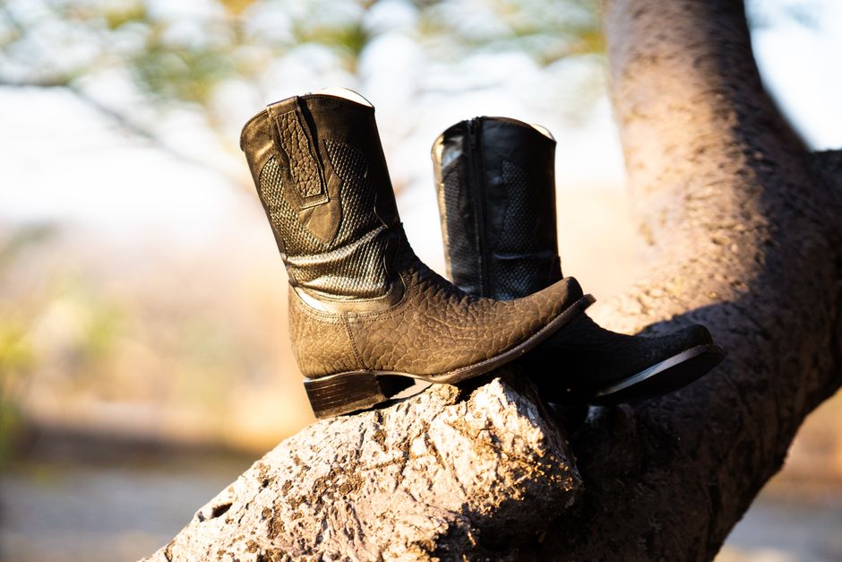 Close-up of cowboy boots on a tree branch, capturing an earthy and western aesthetic.