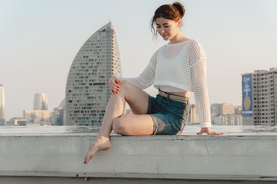 Woman sitting on rooftop with city skyline in the background, enjoying the sunset.