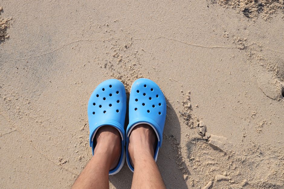 Blue rubber sandals on sandy beach, perfect for summer style and beach travel.