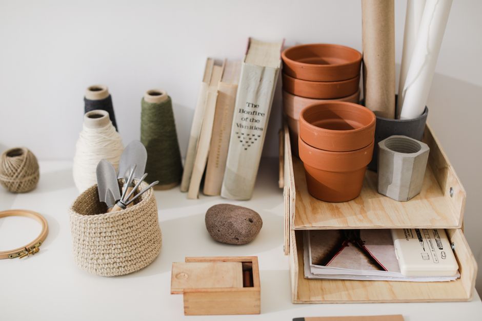 A well-organized workspace featuring books, threads, tools, and flower pots, perfect for creativity.