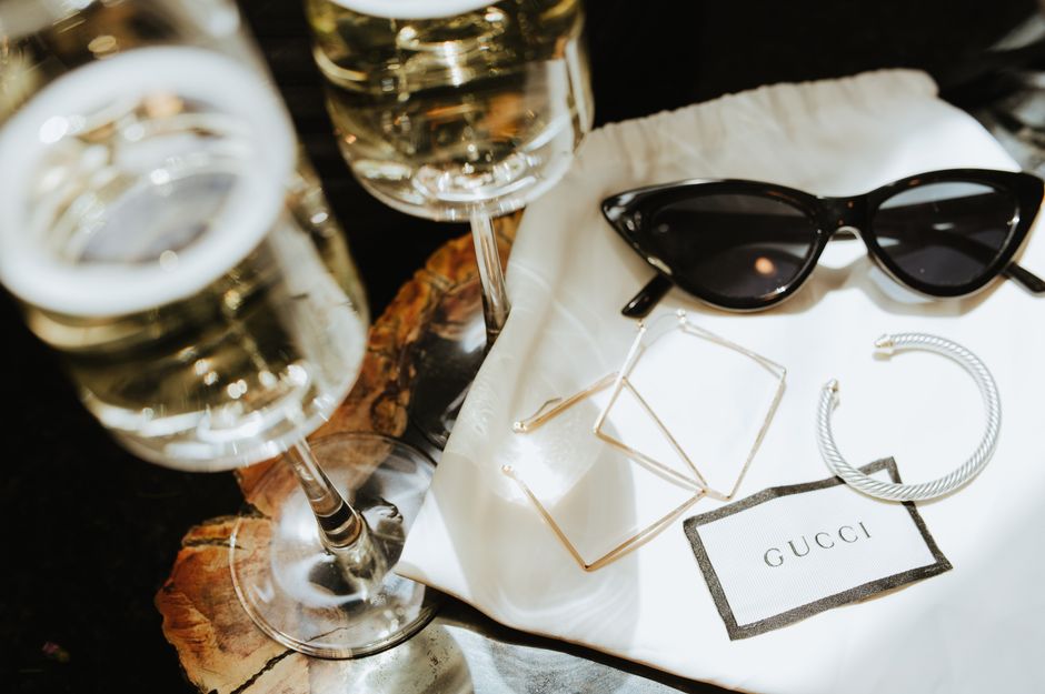 Elegant Gucci sunglasses and jewelry with champagne on a dark background, perfect for a luxury lifestyle theme.