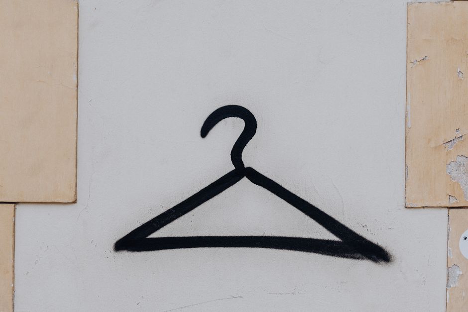 Black hanger graffiti art on a white urban wall, showcasing minimalism in street art.