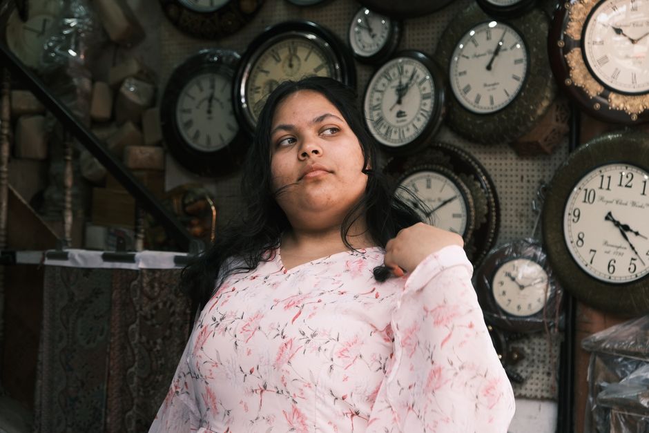 A woman poses in a Bengaluru shop surrounded by vintage clocks, adding a timeless aesthetic.