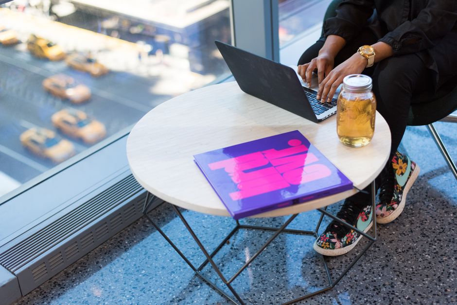 Urban workspace with a laptop, colorful book, and city view, highlighting modern working lifestyle.