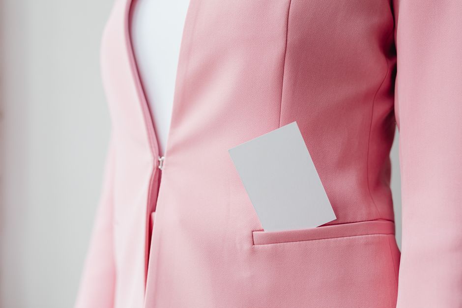 Close-up of a pink blazer featuring a business card in the pocket, stylish and professional.
